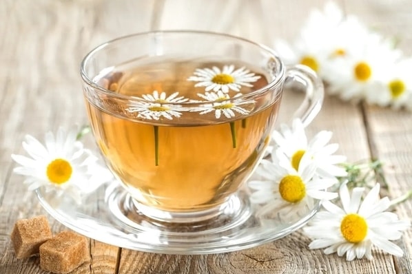 Heřmánkový čaj s květy heřmánku ve skleněném hrnečku
