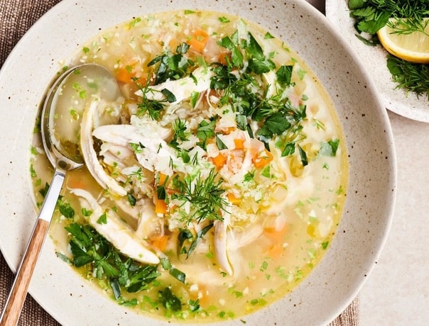 Květákovo-rýžová polévka se zeleninou, bylinkami a kuřecím masem v hlubokém keramickém talíři