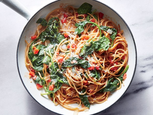 Celozrnné špagety se špenátem, česnekem, parmezánem a rajčaty v kovové pánvi