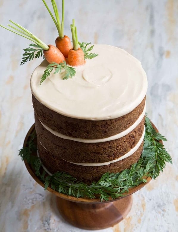 Zdravý velikonoční mrkvový dort s řeckým jogurtem a čerstvou mrkví na dřevěném dortovém podnose