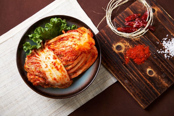 Zátiší se zdravým kimchi, salátem, solí a kořením na dřevěném prkýnku