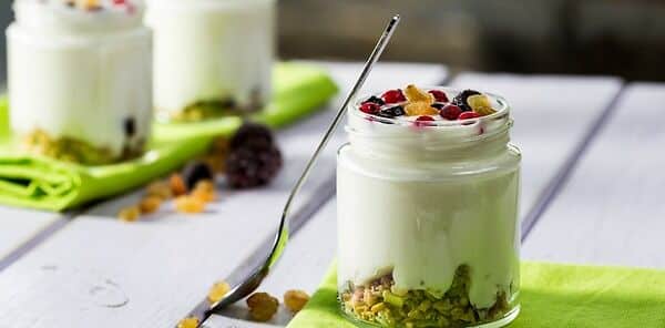 Řecký jogurt s ovocem a ořechy ve sklenici se lžičkou