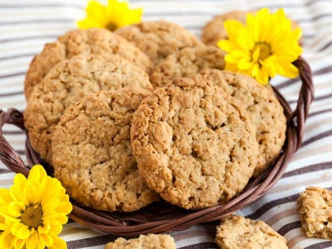 Zdravé ovesné sušenky s arašídovým máslem a čerstvými květy v proutěném košíčku