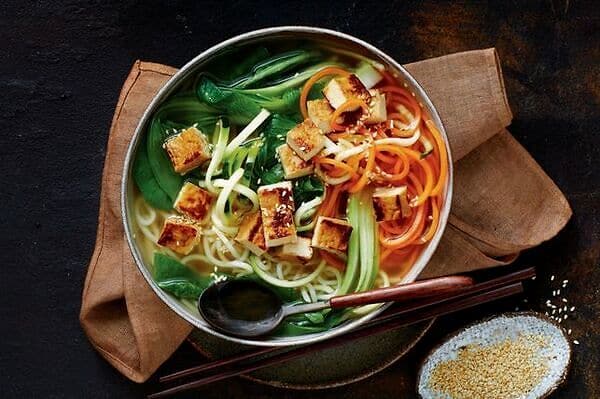 Zdravé večeře bez masa - zdravé ramen nudle se zeleninou a tofu v keramické misce se lžící
